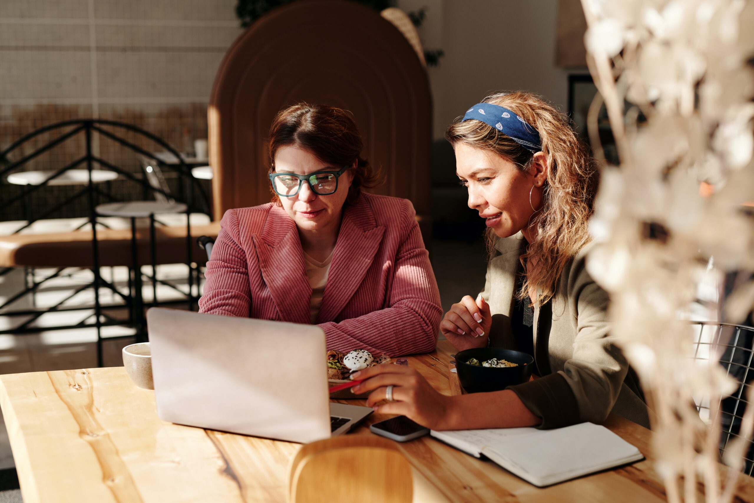 Two women work on a computer reviewing their finance report translation