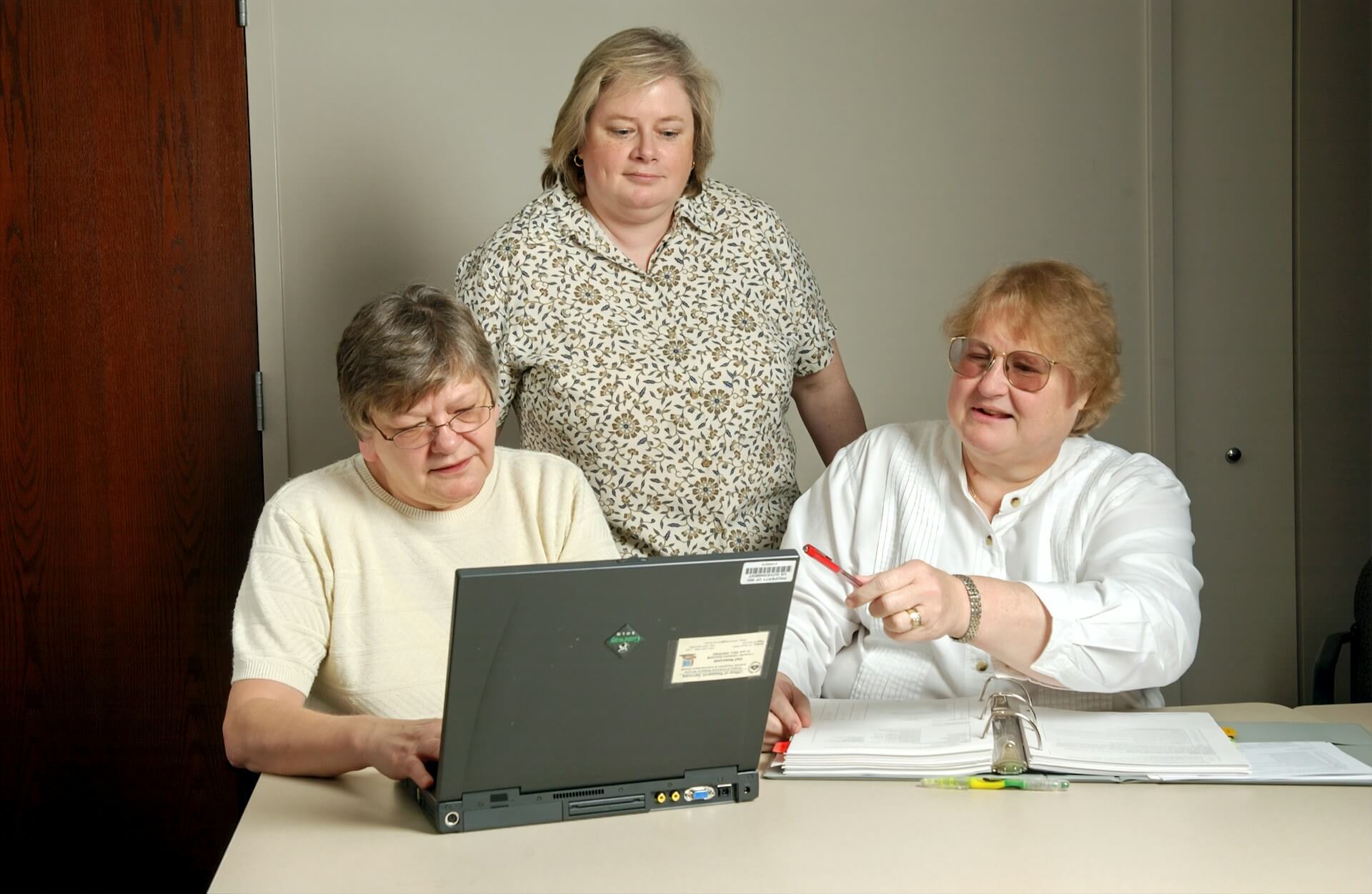 Three women around a laptop working to comply with the European Accessibility Act (EAA)