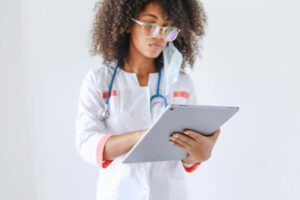 A woman doctor using an electronic device to navigate through clinical research data.