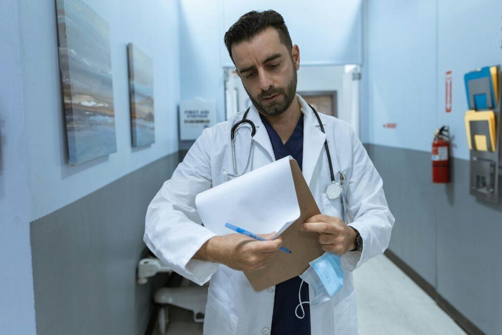 Un médico rellena un formulario mientras camina por el pasillo de un hospital.