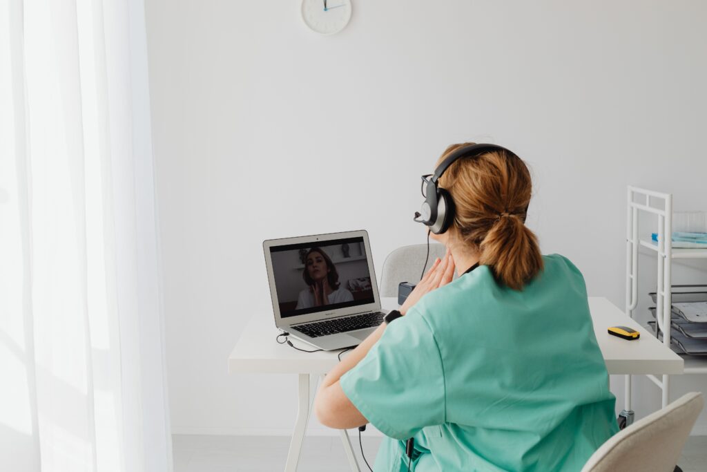A doctor and a patient during a telehealth consultation on a laptop, which professional interpreters can support.